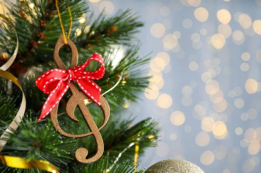 Tahta bir nota ve kırmızı bir fiyonk, bulanık ışıklara karşı Noel ağacında asılı. Metin için boşluk