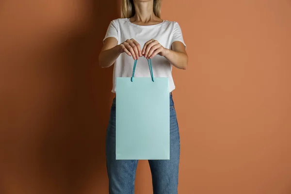 薄い茶色の背景に紙の買い物袋を持つ女性 クローズアップ — ストック写真