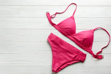 Beyaz ahşap arka planda güzel pembe bikini, üst manzara. Metin için boşluk