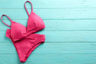 Açık mavi ahşap arka planda güzel pembe bikini, üst manzara. Metin için boşluk