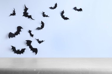Kağıt yarasalarla dekore edilmiş beyaz duvarın yanındaki boş gri masa, yazı için yer. Cadılar Bayramı