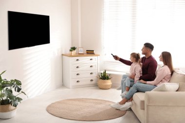 Mutlu bir aile evdeki kanepede televizyon izliyor.
