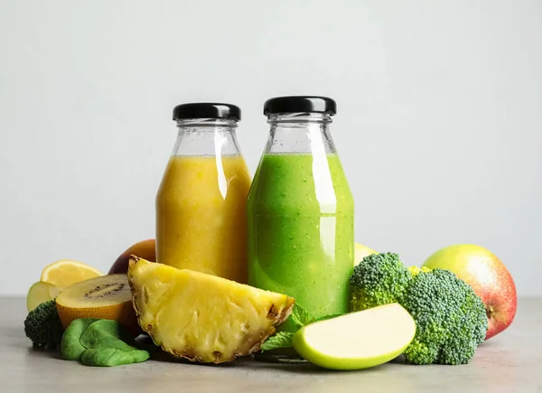 Flaskor Med Läckra Juicer Och Färsk Frukt Grått Bord — Stockfoto