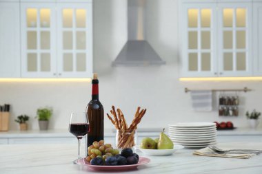 Modern mutfakta kırmızı şarap ve aperatifler beyaz masada. Metin için boşluk
