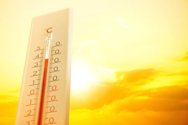 Hava durumu termometresi arka planda bulutlu ve güneşli gökyüzünü gösteriyor