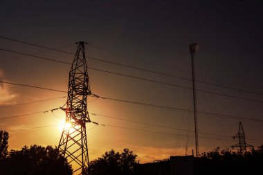 Akşamları yüksek voltaj kulesi ve ağaçların siluetleri