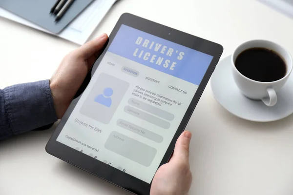 Man Met Tablet Met Rijbewijs Aanvraagformulier Aan Witte Tafel Close — Stockfoto