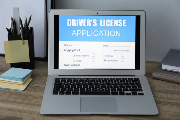 Laptop with driver\'s license application form on table in office