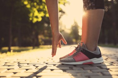 Parkta sabah koşusundan önce esneme hareketleri yapan bir kadın. Metin için boşluk