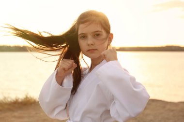 Gün batımında nehirde karate yapan kimonolu tatlı bir kız.