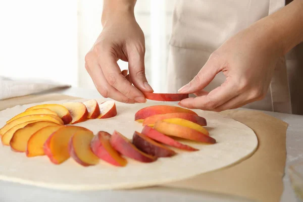 Woman making peach pie at kitchen table, closeup