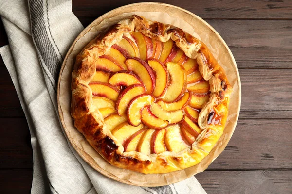 Delicious fresh peach pie on wooden table, top view