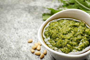 Gri masada bir kase lezzetli roka pesto, yakın plan. Metin için boşluk