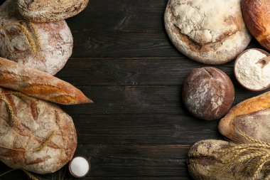 Siyah ahşap masa üzerinde farklı taze ekmek türleri, düz yatıyordu. Metin için boşluk