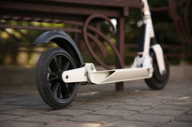 Parktaki bankın yanında modern elektrikli scooter, yakın plan.