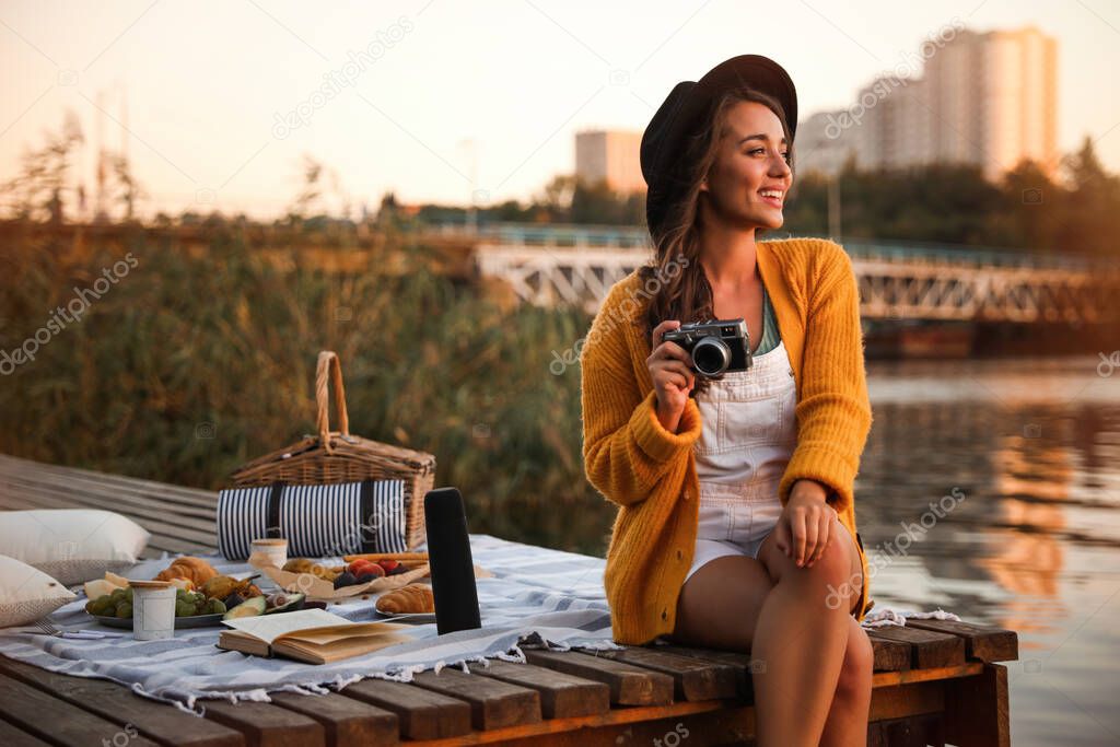 Young woman with camera on pier at picnic
