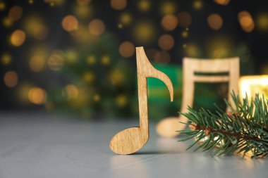 Tahta müzik notası ve açık gri masada köknar dalları bulanık Noel ışıklarına karşı