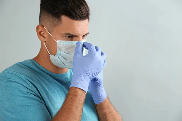 Man Medicinska Handskar Sätta Skyddande Ansiktsmask Mot Grå Bakgrund Plats — Stockfoto