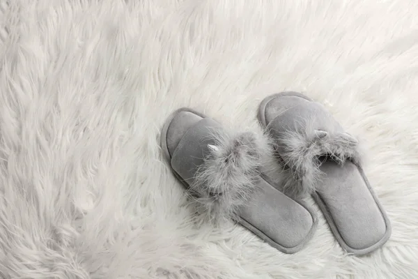 Pair of soft slippers on white faux fur, flat lay. Space for text
