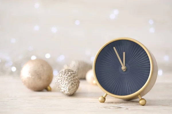ぼやけたクリスマスライトに対する白い木製のテーブルの上に装飾が施されたスタイリッシュな時計は 閉じます 新年のカウントダウン — ストック写真