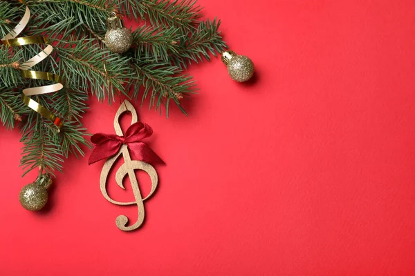 赤い背景にクリスマスの装飾や木製の音楽ノートとモミの木の枝のトップビュー テキストのためのスペース — ストック写真