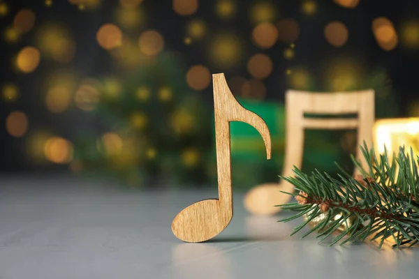 淡灰色桌子上的木制乐谱和冷杉枝条挡住了模糊的圣诞灯火 — 图库照片