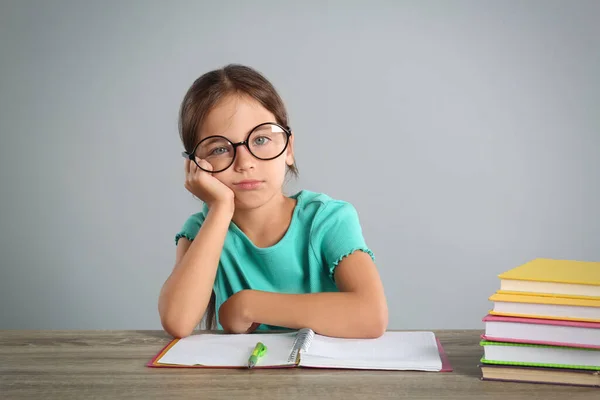 Aburrido Niña Haciendo Tarea Mesa Sobre Fondo Gris — Foto de Stock