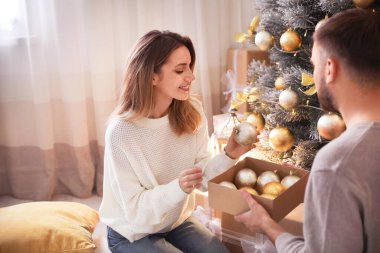 Mutlu çift evde Noel ağacını süslüyor.