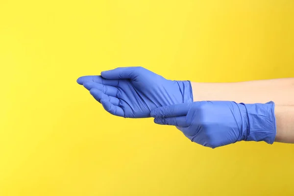 Pessoa Colocando Luvas Médicas Contra Fundo Amarelo Close Mãos — Fotografia de Stock