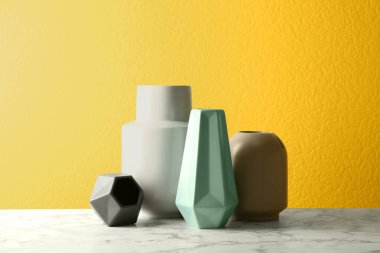 Beyaz mermer masada sarı arka planda seramik vazolar