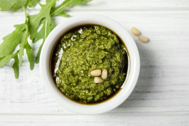 Beyaz ahşap masada bir kase lezzetli pesto ve roka.