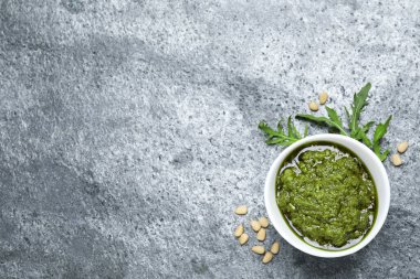 Bir kase lezzetli roka pesto ve gri masa üzerindeki malzemeler. Metin için boşluk