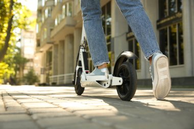 Woman riding electric kick scooter outdoors, closeup. Space for text clipart