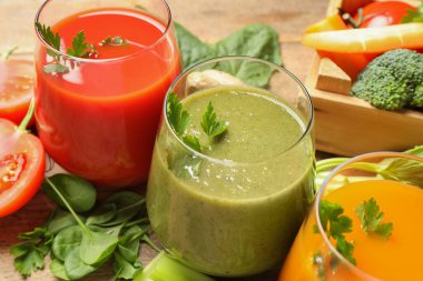 Lezzetli sebze suları ve ahşap masada taze malzemeler, yakın plan.