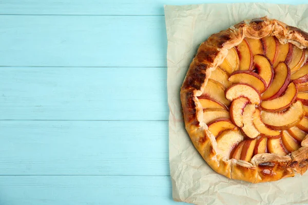 Delicious fresh peach pie on light blue wooden table, top view. Space for text