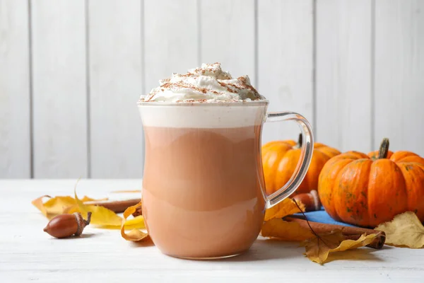 Delicious pumpkin latte on white table, closeup