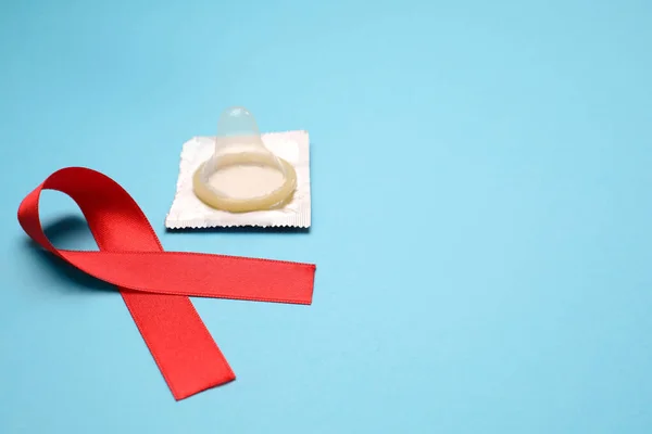 빨간색 리본과 콘돔이 파란색 배경에 텍스트를 공간에 있습니다 Aids 질병에 — 스톡 사진