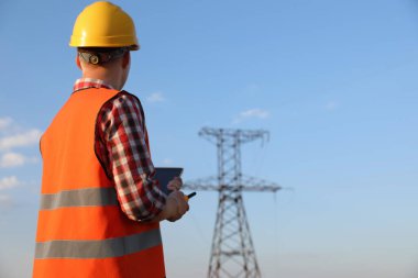 Yüksek voltaj kulesinin yanında telsizi olan elektrik mühendisi.