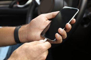 Şarj kablosunu arabadaki akıllı telefona bağlayan adam, kapat