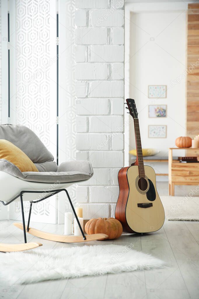 Cozy room interior with rocking chair, guitar and autumn decor