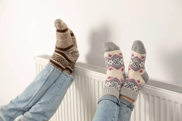 白い壁の近くの暖房ラジエーターの家族の暖かい足 クローズアップ — ストック写真