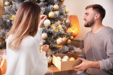 Mutlu çift evde Noel ağacını süslüyor.