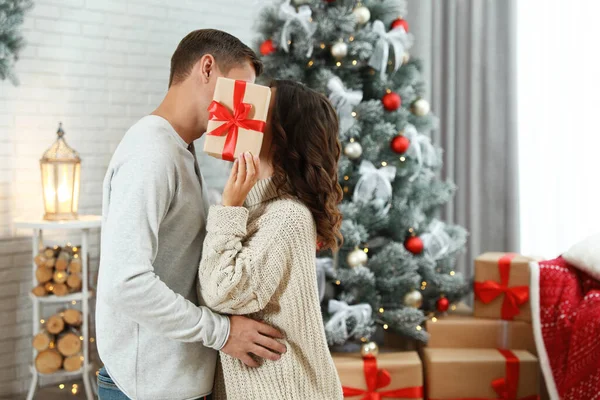 カップル接吻しながら隠れてクリスマスギフトに家 — ストック写真