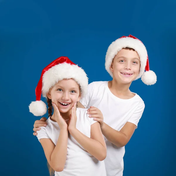 青い背景にサンタの帽子の幸せな小さな子供たち クリスマスのお祝い — ストック写真