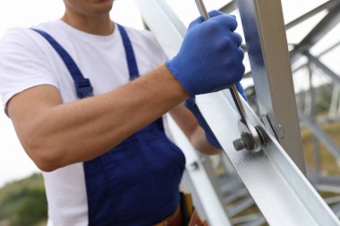 İşçi yüksek voltajlı kule inşaatı, açık hava, yakın çekim. Elektrik santralinin kurulumu