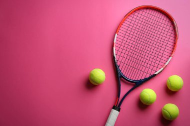 Tenis raketi ve toplar pembe arka planda, düz yerde. Metin için boşluk