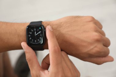 MYKOLAIV, UKRAINE - ECTOBER 04, 2019: Apple Watch kullanan adam ışık arkaplanındaki zamanı kontrol ediyor, yakın plan