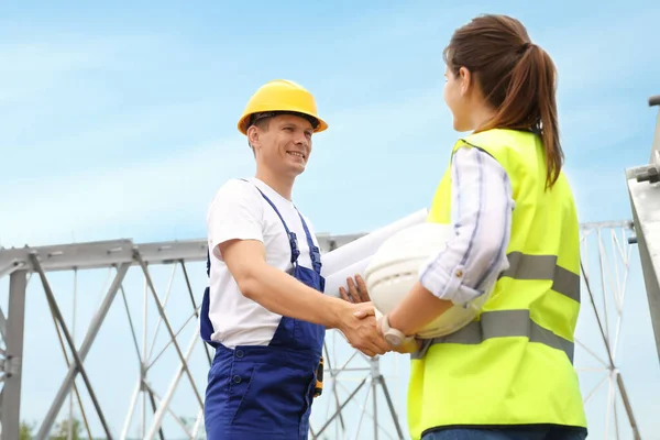 Professional engineers working on installation of electrical substation outdoors