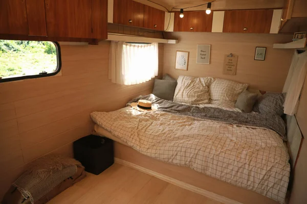 Stylish room interior with comfortable bed and pillows in modern trailer. Camping vacation