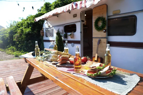 Träbord Med Mat Och Flaskor Nära Trailer Solig Dag Campingsäsong — Stockfoto